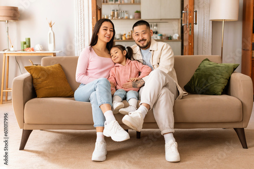 Japanese Father, Mother And Daughter Sitting On Couch At Home