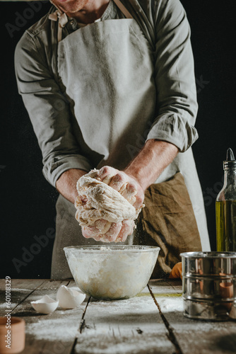 Unrecognizable man in an apron kneading the dough