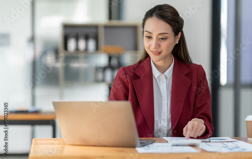 Asian businesswoman clicking details on laptop computer analyzing data checking accuracy of financial income happily in office management concept management.