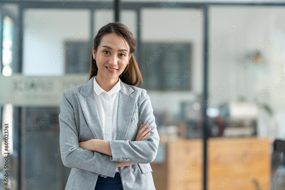 Attractive asian businesswoman standing with crossed arms and looking at camera in office confident and happy with business success Attractive asian businesswoman standing with crossed arms and looking at camera in office confident and happy with business success
