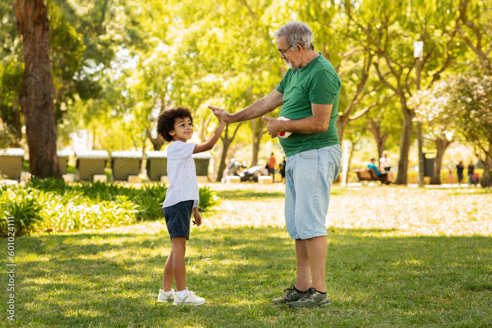 Positive little black boy and old caucasian grandfather enjoy free time, have fun, play football Positive little black boy and old caucasian grandfather enjoy free time, have fun, play football