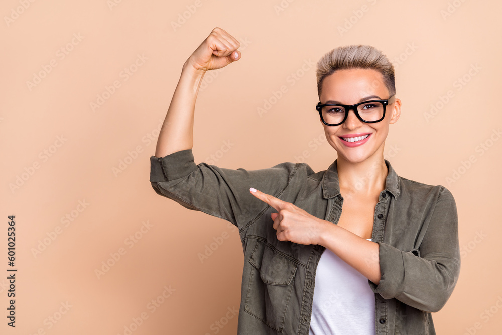 Photo of young business lady wear khaki shirt fist up show her muscle biceps finger point woman power isolated on beige color background