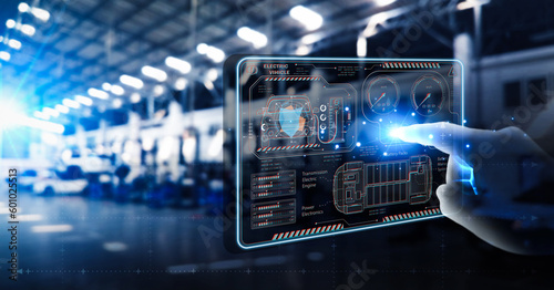 EV electric vehicle technology industry concept, futuristic virtual graphic touch user interface on screen with auto repair garage blurred on background.
