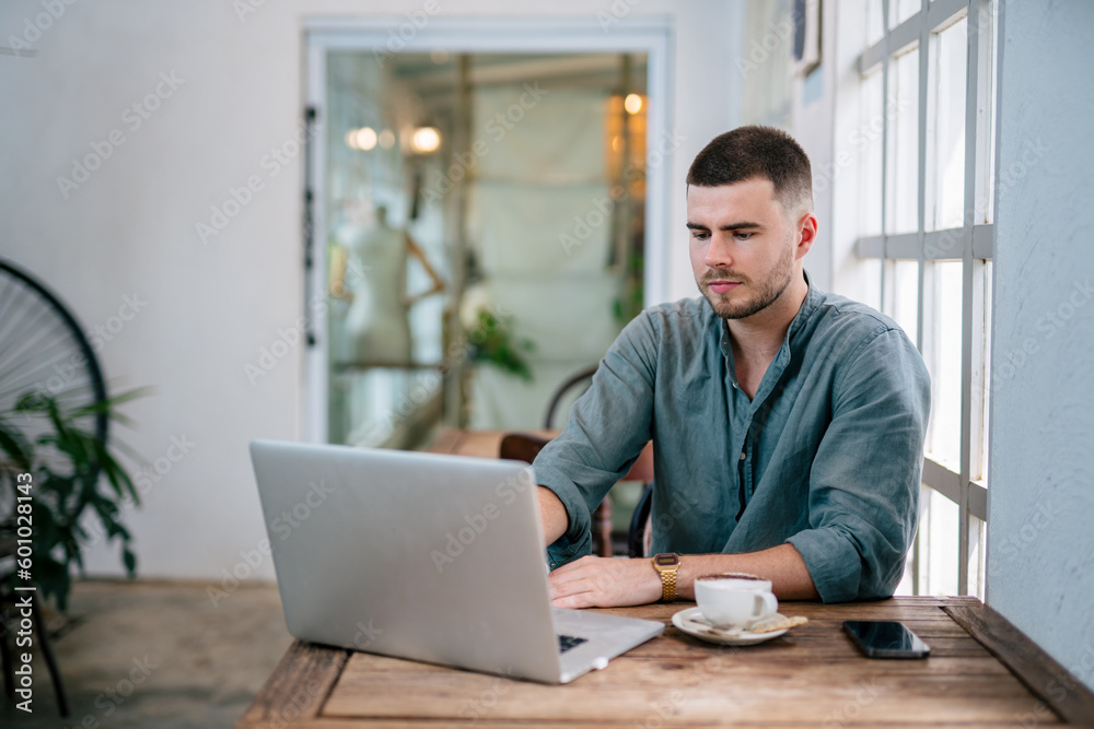 A Handsome young man sitting on laptop reading online news. freelance concept. A Handsome young man sitting on laptop reading online news. freelance concept.