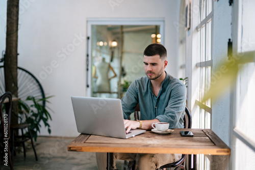 A male, Handsome Freelancer bearded man using a laptop sitting at a table. freelance concept.