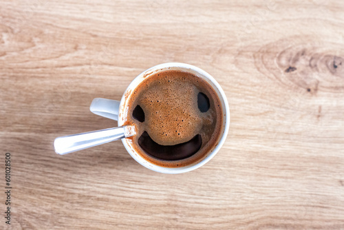 Coffee cup with funny smiling face, top view. Coffee open smile mouth in white mug, pareidolia effect