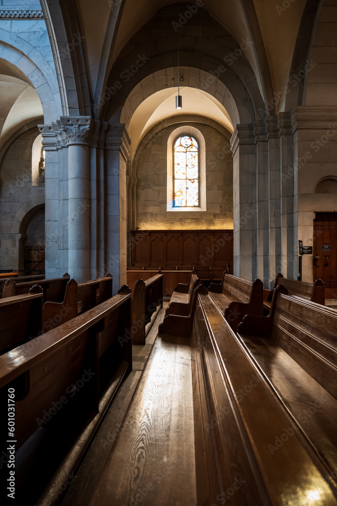 Sunlight beaming down on empty wooden church pews. Wide angle view, no people