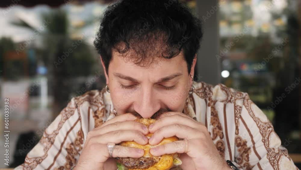 Hispanic guy eating burger. Junk food, modern life concept. Hispanic guy eating burger. Junk food, modern life concept.