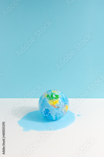 Global warming concept with the world globe melting on white and blue background. Vertical view