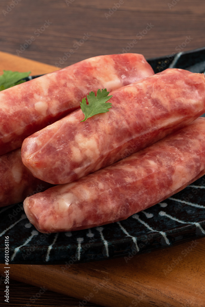Raw Taiwanese sausage in garlic flavor in a plate on wooden table background. Raw Taiwanese sausage in garlic flavor in a plate on wooden table background.