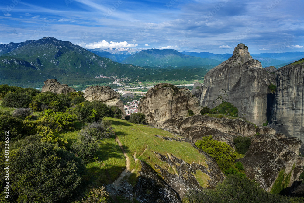 View from the Meteora rocks over the village Kalambaka in the valley to the mountains and snow-capped peaks, landscape in central Greece, cloudy blue sky, copy space, selected focus