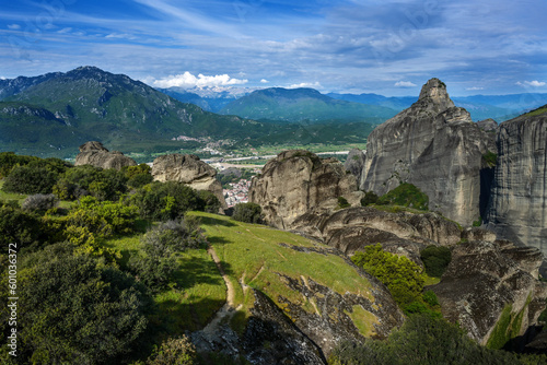 View from the Meteora rocks over the village Kalambaka in the valley to the mountains and snow-capped peaks, landscape in central Greece, cloudy blue sky, copy space, selected focus