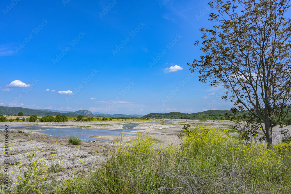 Dried up riverbed of the Pinios near Kalambaka in Thessaly, Greece, low water after heat and drought, potential effect of global climate warming, wide landscape under a blue sky, copy space