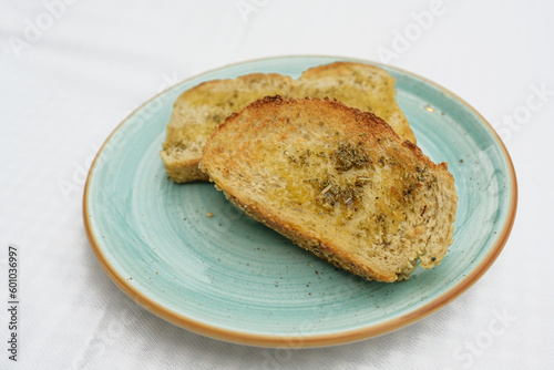 toasted bread with olive oil, herbs and garlic salt on a blue plate, copy space, selected focus, narrow depth of field