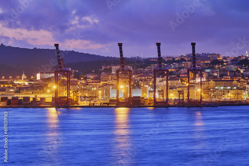 View of Lisbon port with port cranes in the evening twilight over Tagus river. Lisbon, Portugal