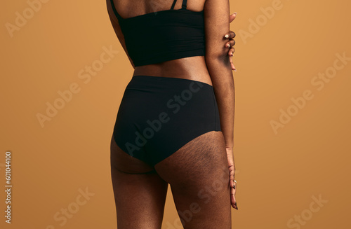 Crop faceless black lady with stretch marks standing in beige studio