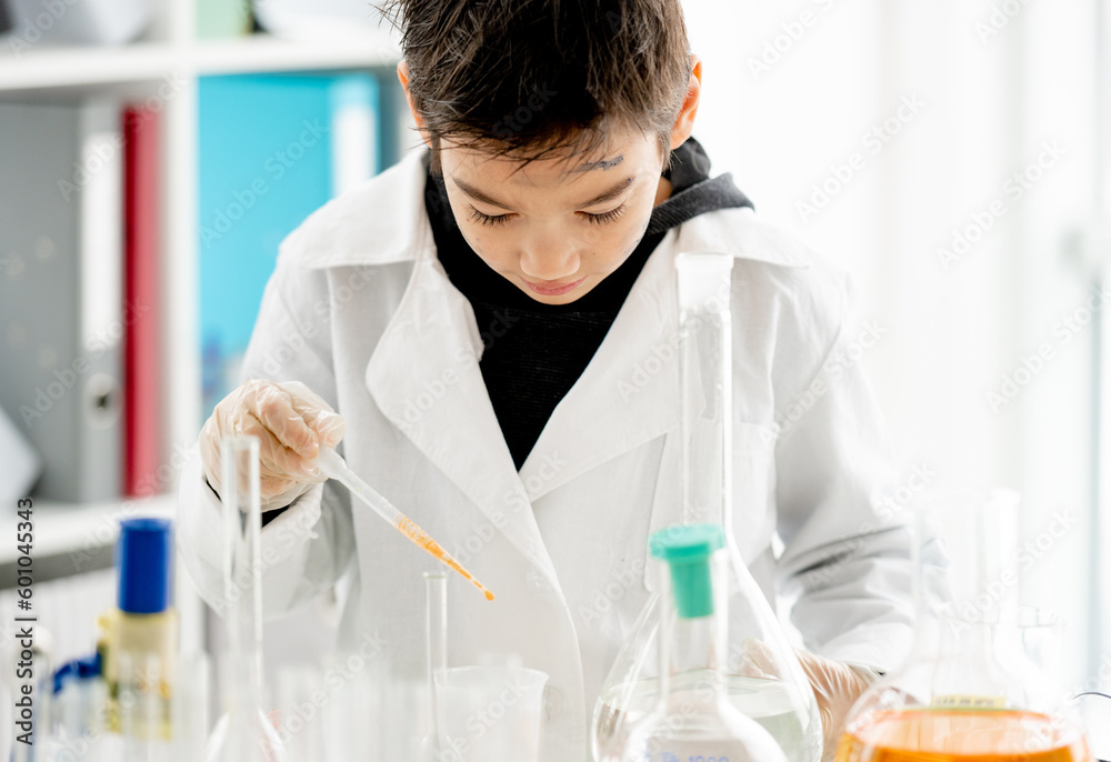 School boy doing chemistry experiment measuring chemical liquids in elementary science class. Clever pupil analyzing results of test in lab School boy doing chemistry experiment measuring chemical liquids in elementary science class. Clever pupil analyzing results of test in lab