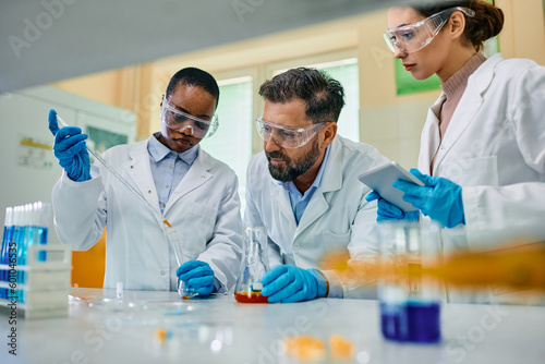 Multiracial team of pharmaceutical chemists working on scientific research together in laboratory. photo