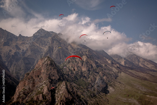 Paragliding flight among rocky mountains and clouds. A sunny, spring day. Extreme, leisure, sports, hobbies. Cover, calendar, wallpaper, screensaver. Kabardino-Balkaria.