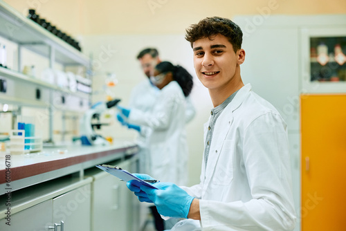 Young happy scientist working on new research in laboratory and looking at camera.