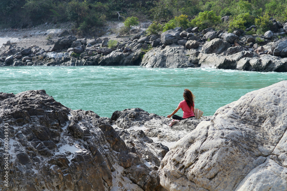 A girl meditates on the banks of the Ganges River in Rishikesh, India.