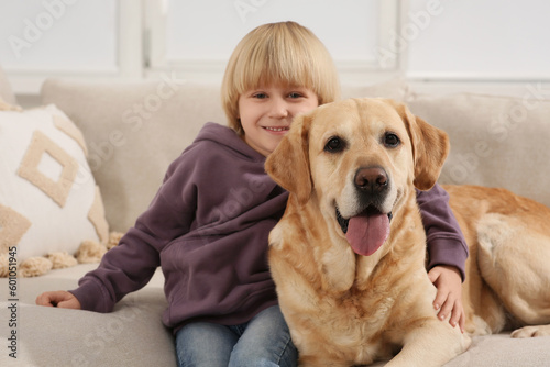 Wallpaper Mural Cute little child with Golden Retriever on sofa at home. Adorable pet Torontodigital.ca