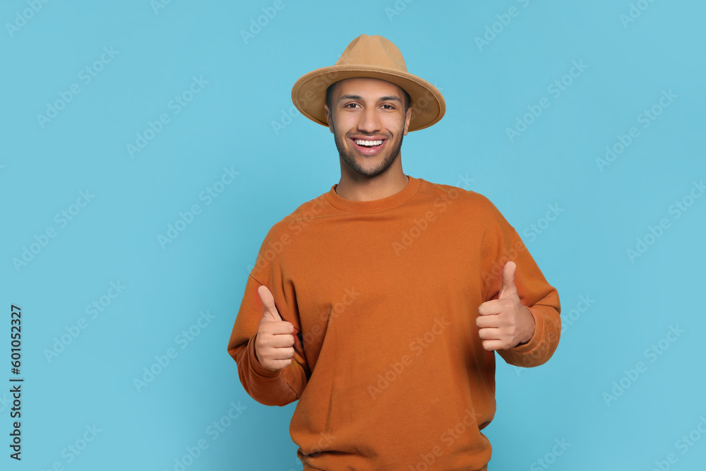 Happy African American man showing thumbs up on light blue background. Space for text Happy African American man showing thumbs up on light blue background. Space for text