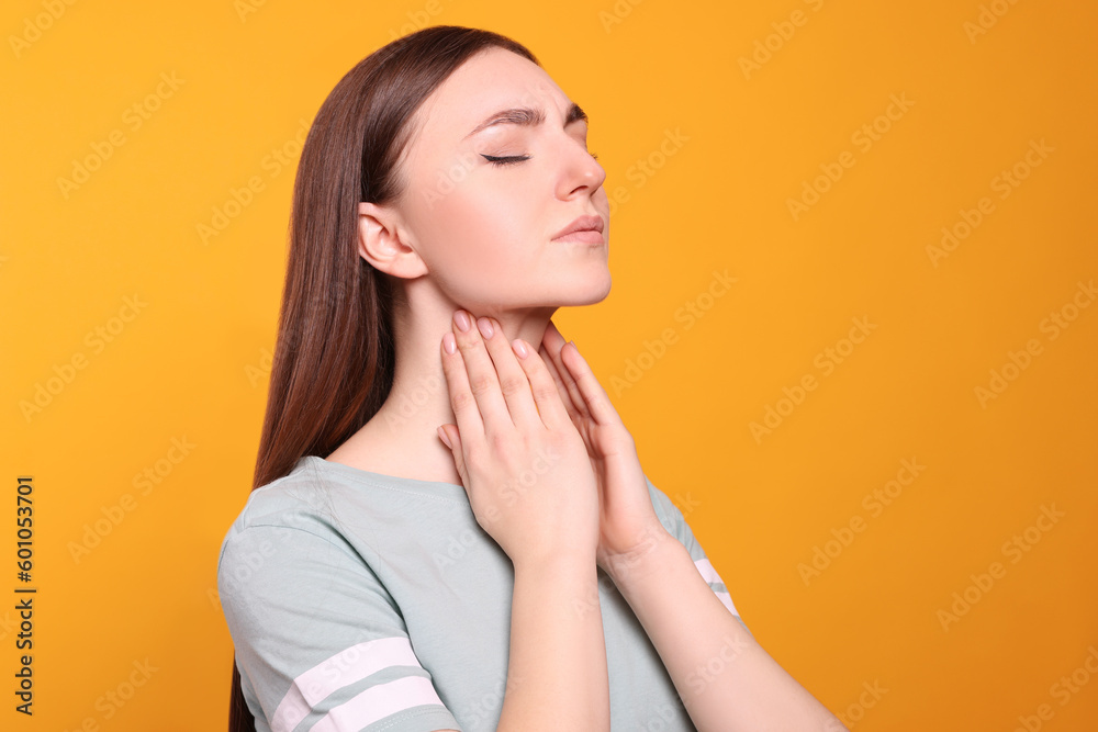Young woman with sore throat on orange background Young woman with sore throat on orange background