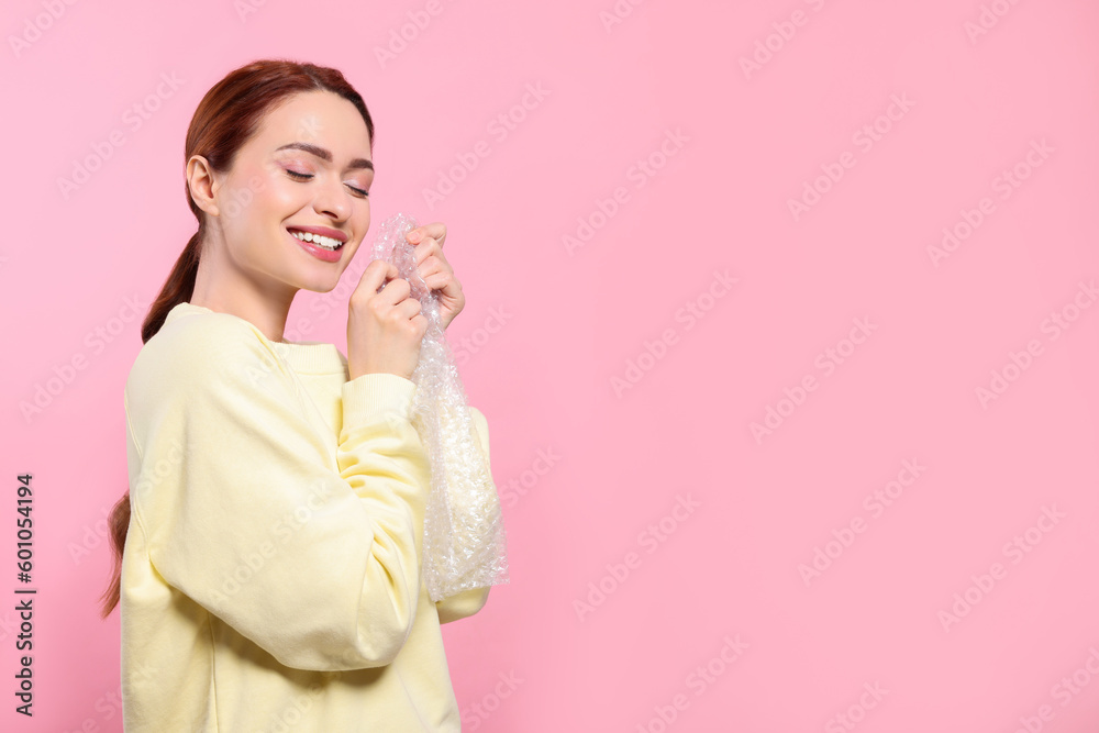 Woman popping bubble wrap on pink background, space for text. Stress relief Woman popping bubble wrap on pink background, space for text. Stress relief