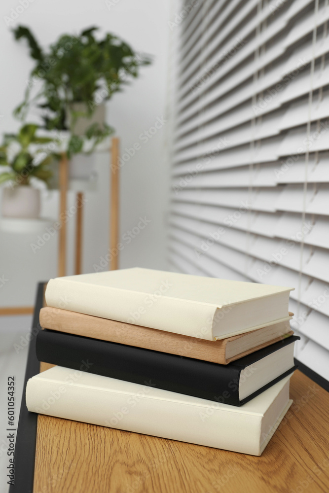 Stack of hardcover books on wooden table indoors Stack of hardcover books on wooden table indoors