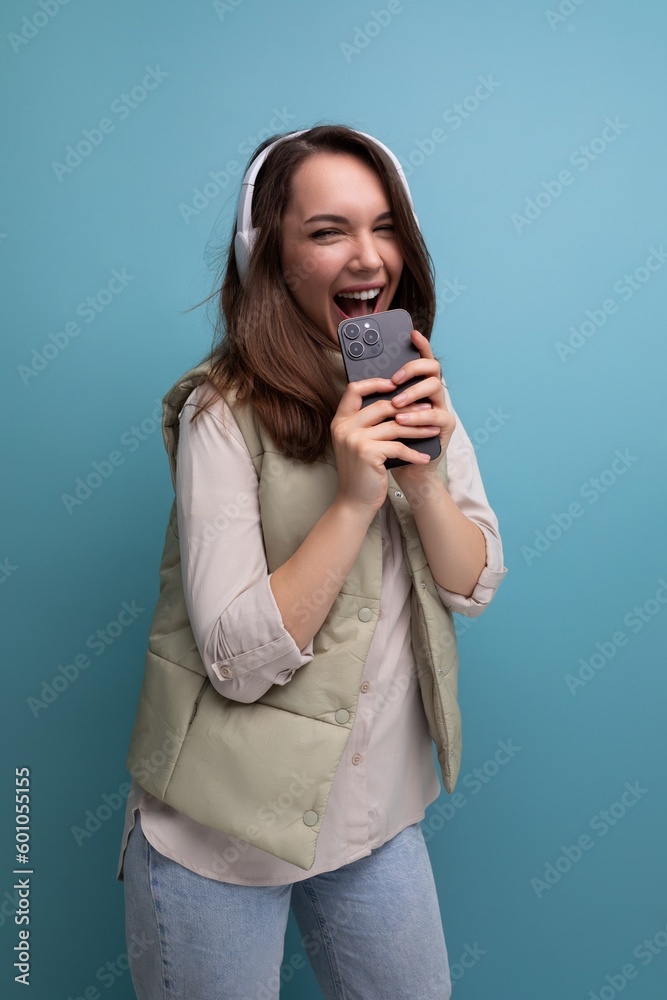 energetic young brunette woman relaxing to music using headphones and mobile phone energetic young brunette woman relaxing to music using headphones and mobile phone