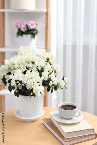 Wallpaper Mural Beautiful azalea plant in flower pot, cup of coffee and books on wooden table in room Torontodigital.ca