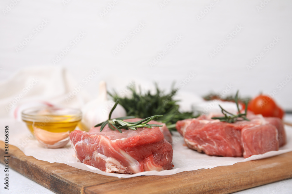 Fresh raw meat with rosemary on wooden board, closeup