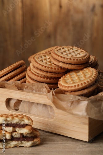 Tasty sandwich cookies with cream on wooden table, closeup