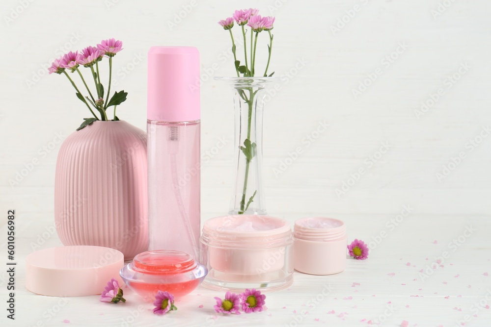 Homemade cosmetic products and beautiful flowers on white wooden table. Space for text