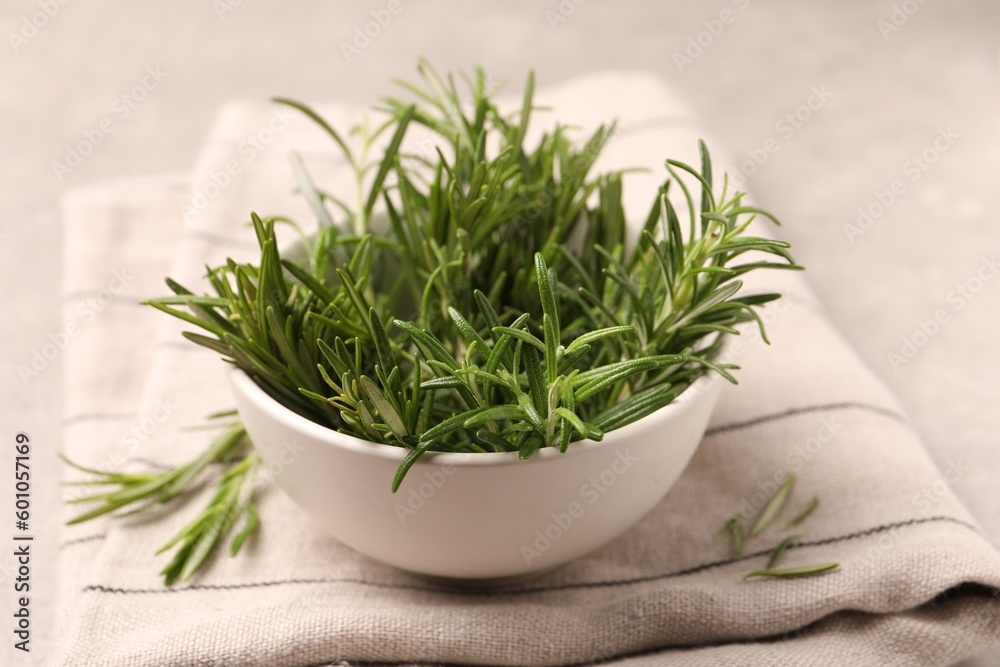 Bowl with fresh green rosemary on light table
