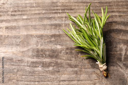 Bunch of fresh green rosemary on wooden table  top view. Space for text