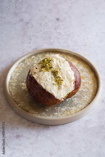 Pistachio Maritozzo on a plate, an italian roman breakfast sweet, whipped cream sandwiched between brioche