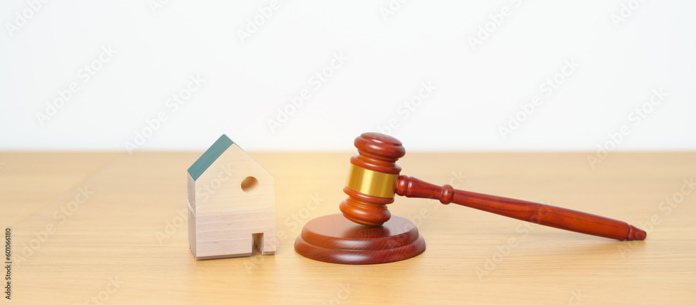 Real Estate Law, Home Insurance, property Tax, Auction and Bidding concepts. small toy house model with gavel justice hammer on desk in courthouse.