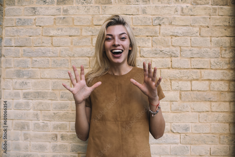 Happy woman showing all fingers while standing at brick wall - obrazy, fototapety, plakaty 