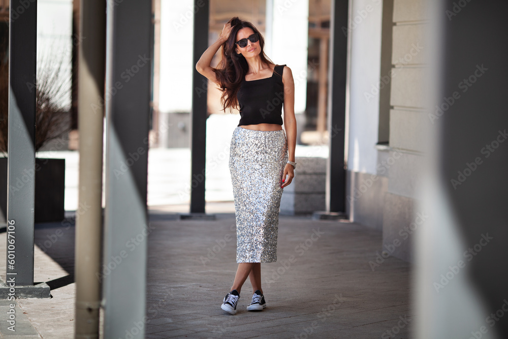 Fashionable woman wears shiny maxi skirt with sequins black sneakers and Tshirt. Fashion street style clothing. Adult female model with long dark hair Stock Photo Adobe Stock