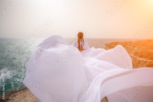Woman sea white dress. Happy freedom woman on the beach enjoying and posing in white dress. Rear view of a girl in a fluttering white dress in the wind. Holidays, holidays at sea. © svetograph
