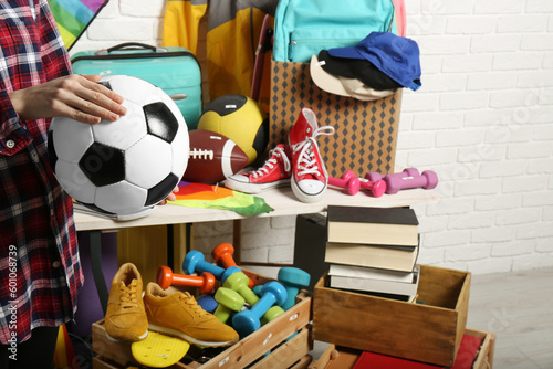 Woman holding ball near many different stuff indoors, closeup. Garage sale photo