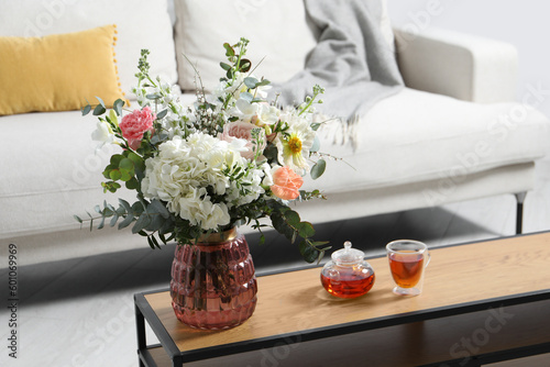 Bouquet of beautiful flowers and tea on wooden table indoors