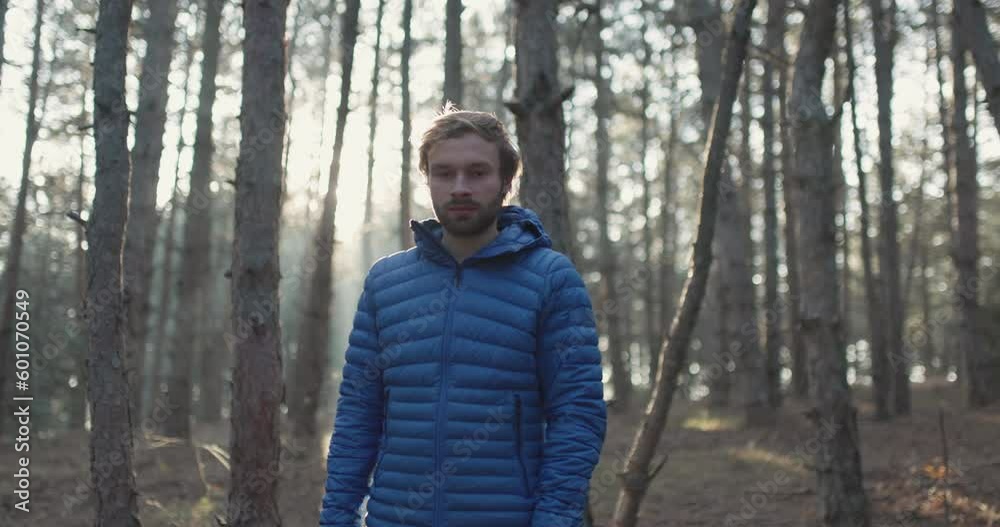 Portrait of a trail runner man standing in the woods. Sun shining through trees in a forest on sunset. Portrait of a trail runner man standing in the woods. Sun shining through trees in a forest on sunset.
