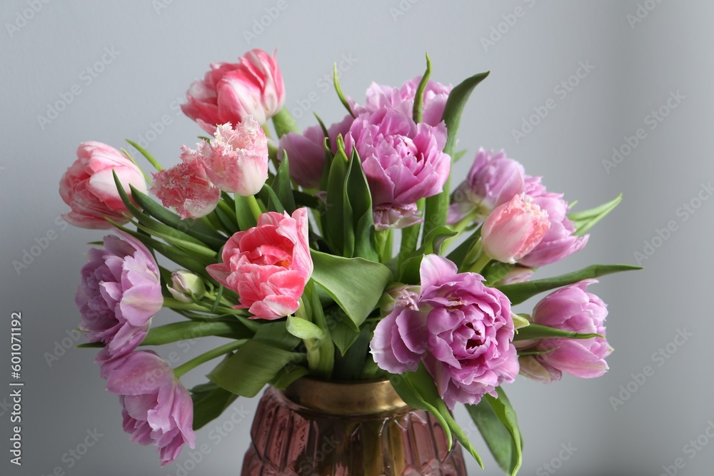 Beautiful bouquet of colorful tulip flowers near light grey wall, closeup Beautiful bouquet of colorful tulip flowers near light grey wall, closeup