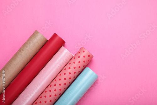 Rolls of colorful wrapping paper on pink background, flat lay. Space for text