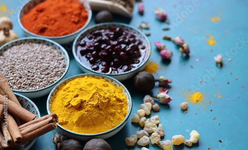 Spices and herbs on turquoise background with copy space. Food and cuisine ingredients. Colorful spices in bowls on blue background, top view
