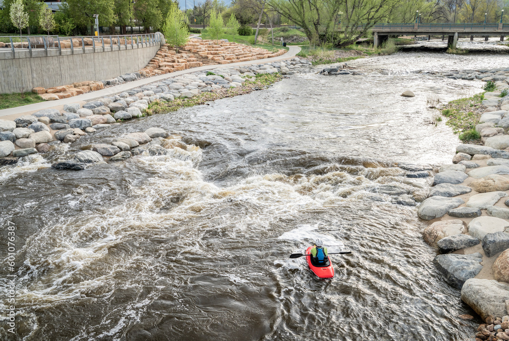 lonely kayaker surfing the wave in Whitewater Park on the Poudre River in downtown of Fort Collins, Colorado lonely kayaker surfing the wave in Whitewater Park on the Poudre River in downtown of Fort Collins, Colorado