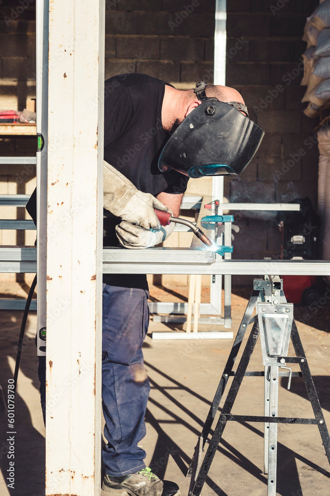 Man in protective mask welding an aluminum structure Man in protective mask welding an aluminum structure